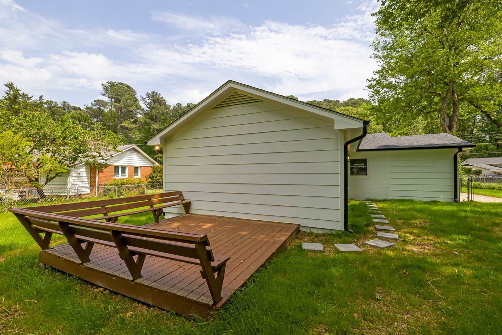 New wooden deck with built-in benches on a green backyard lawn