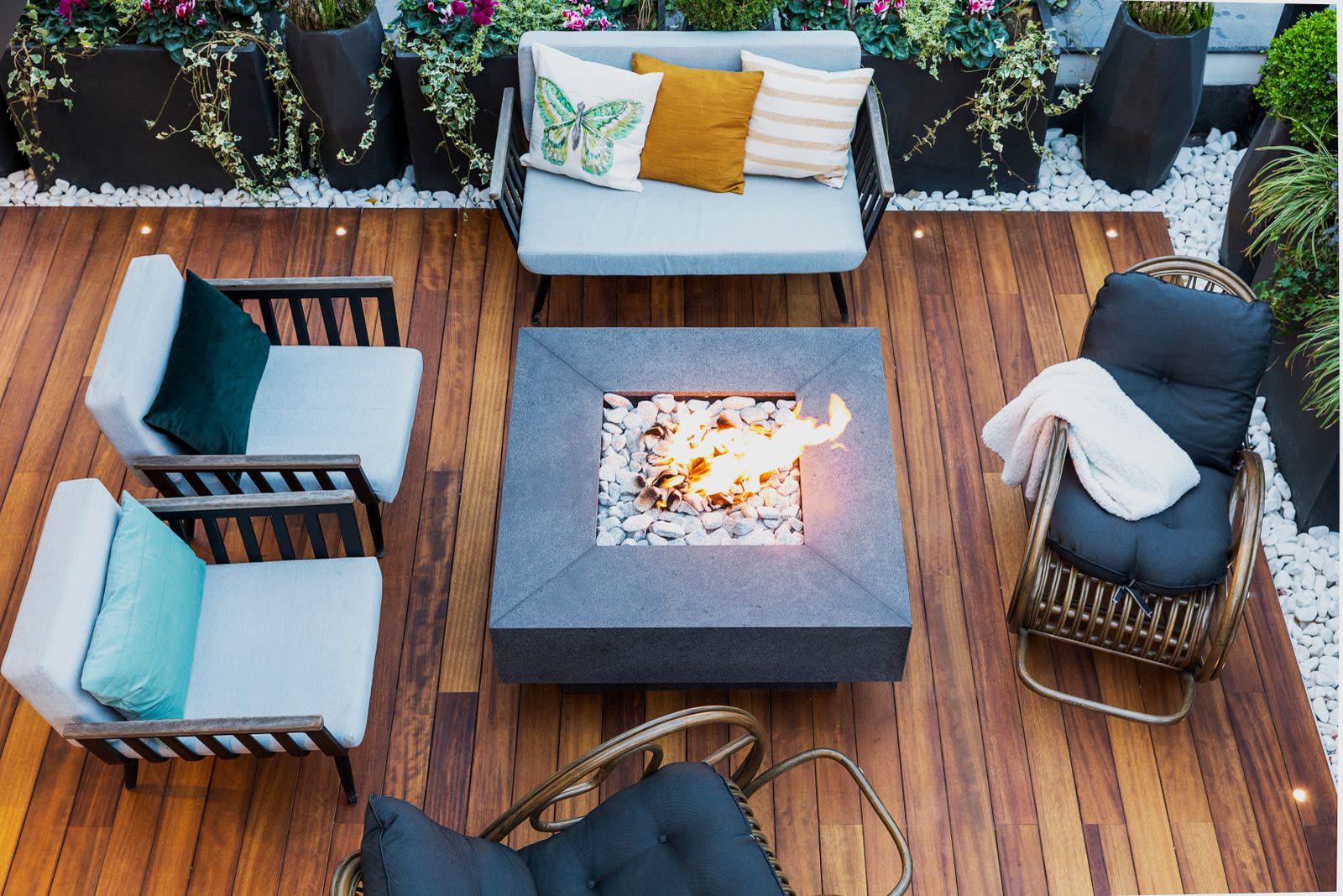 Overhead view of a wooden deck with a fire pit and lounge chairs