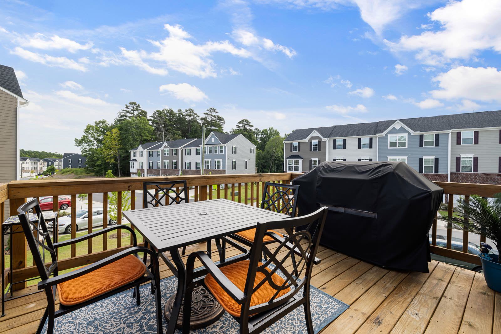 Wooden deck with patio furniture and a grill outside townhomes